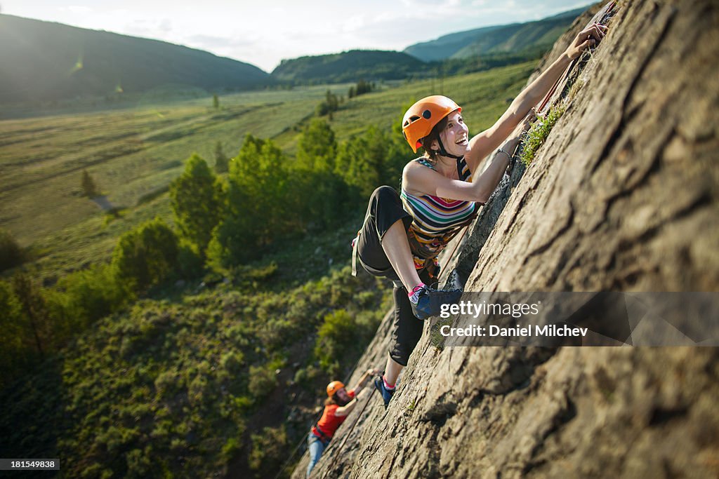 Guy and a girl, rock climbing during sunset.