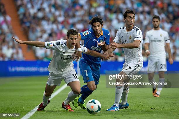 Angel Lafita of Getafe CF competes for the ball with Nacho Fernandez of Real Madrid CF and his teammate Alvaro Arbeloa during the La Liga match...