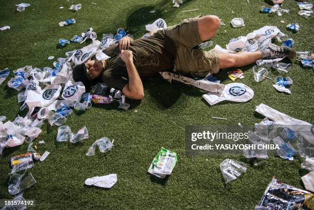 Man sleeps on the ground among trash during the Rock in Rio music festival in Rio de Janeiro, Brazil, on September 22, 2013. AFP PHOTO / YASUYOSHI...