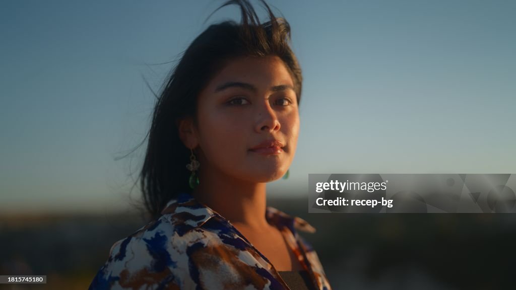 Retrato de la hermosa mujer turista multirracial durante la puesta del sol en la cima de la colina