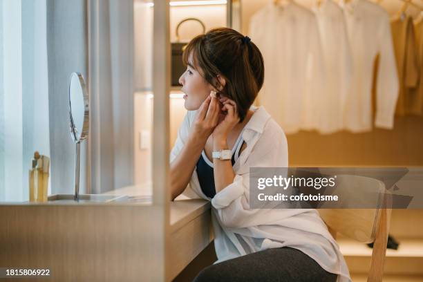 happy asian woman trying on earrings in front of the mirror at home, - walk in closet stock pictures, royalty-free photos & images