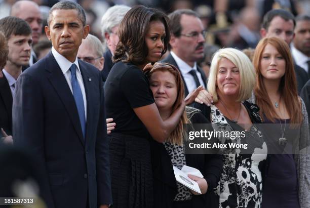 President Barack Obama pauses as first lady Michelle Obama hugs a family membr during a memorial service for victims of the Washington Navy Yard...