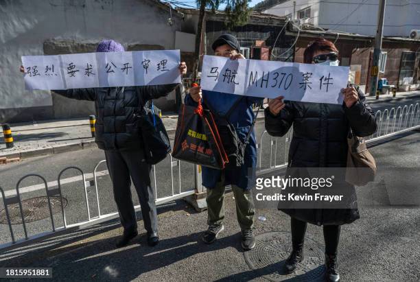 People whose relatives were passengers on Malaysian Airlines flight 370 hold signs demanding a public trial as they meet journalists after a hearing...