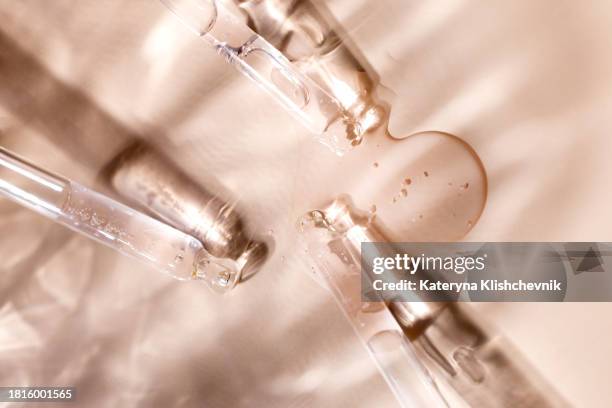 glass pipettes with drops of transparent serum on a beige background, skin care cosmetics concept - retinol stock pictures, royalty-free photos & images