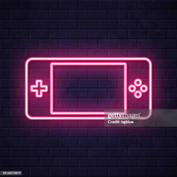 handheld game console. glowing neon icon on brick wall background - touch screen wall stock illustrations