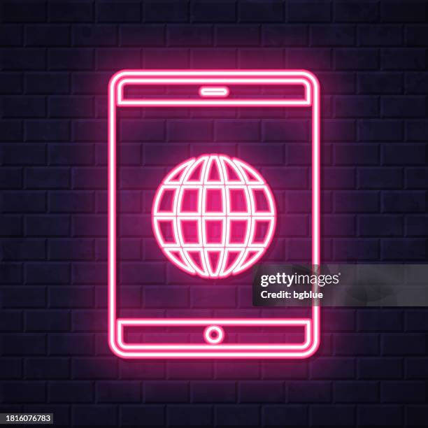 tablet pc with globe. glowing neon icon on brick wall background - touch screen wall stock illustrations