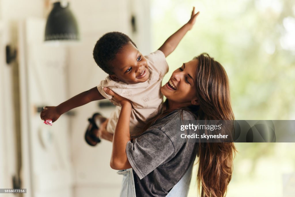 Happy single mother having fun with her adopted black son at home.