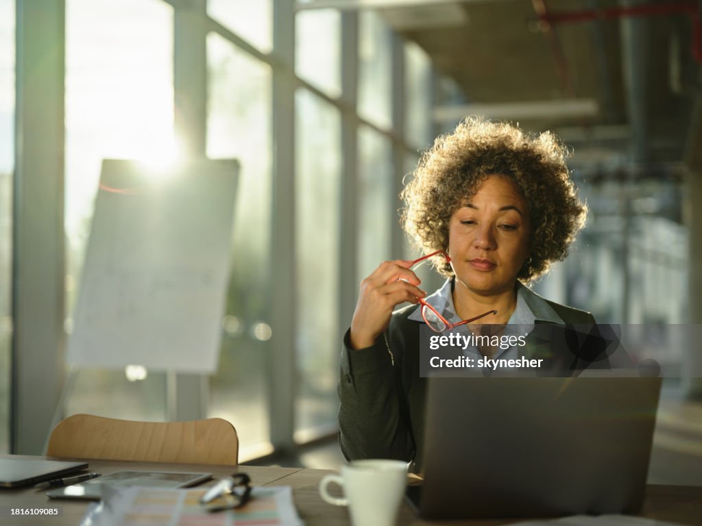 Nachdenkliche Geschäftsfrau, die im Büro am Laptop arbeitet.