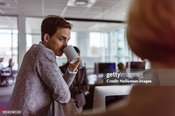 colegas que toman un café y charlan amistosamente - cotilleo fotografías e imágenes de stock