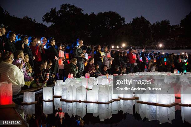 People watch floating lanterns in a temporary man-made pond in Central Park during a ceremony dedicated to honoring peace and peace makers on...