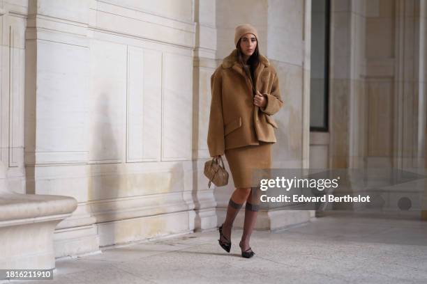 Gabriella Berdugo wears a total beige look from Miu Miu, a beige wool ribbed cashmere beanie hat, a brown oversized corduroy jacket from Miu Miu, a...