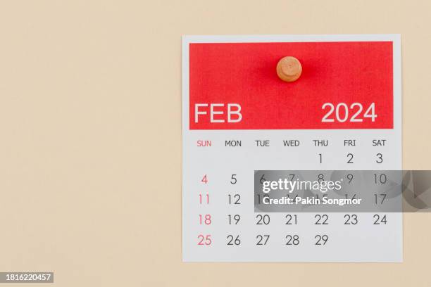 desk calendar 2024: february calendar is used to plan daily work and life with a push pin on a beige color paper background. - february stock pictures, royalty-free photos & images