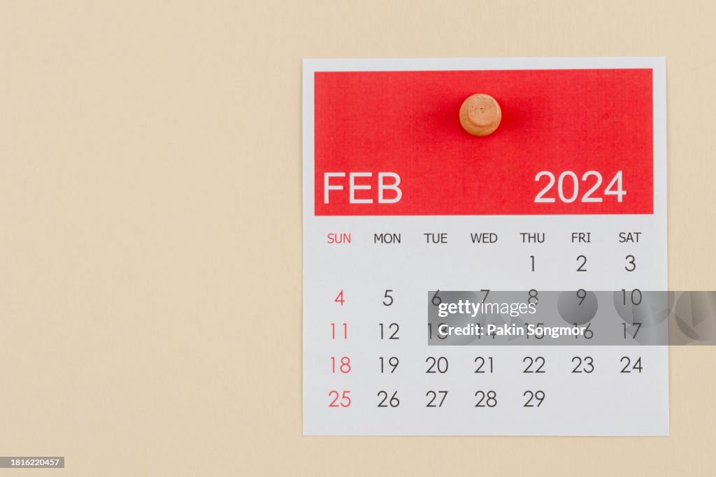 Desk Calendar 2024: February calendar is used to plan daily work and life with a push pin on a beige color paper background.
