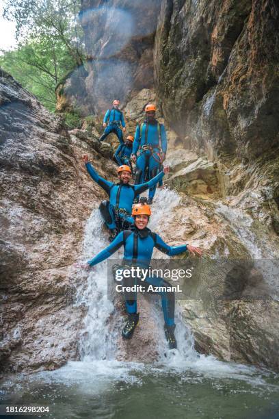 fun times with diverse participants canyoning - waterfall jump stock pictures, royalty-free photos & images
