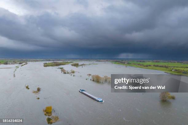 Frieght ship sailing on the river IJssel with high water level on the floodplains of the river IJssel after a long period of heavy rain upstream...