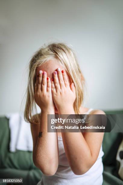 concealing identity: close-up portrait, girl child hiding face behind colorful nails and palms. - gesicht verstecken stock-fotos und bilder