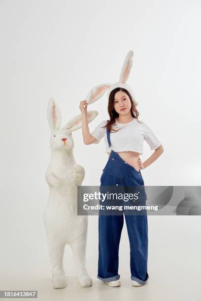 a cute young pregnant woman wears a headband with bunny ears in bib pants - bunny ears stockfoto's en -beelden