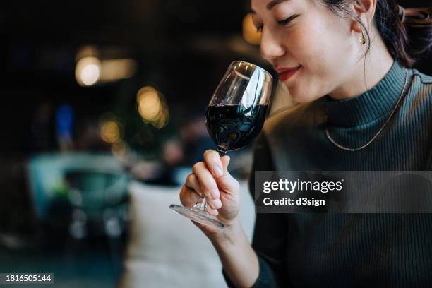 beautiful young asian woman drinking glass of red wine in restaurant. wine tasting experience. luxury lifestyle. people, food and lifestyle - prova de vinho imagens e fotografias de stock