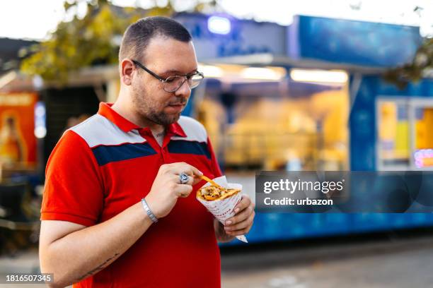 erwachsener mann isst gyros auf der straße - gyros stock-fotos und bilder