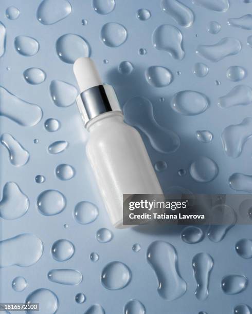 cosmetic glass bottle with facial moisturizing serum on trendy colored blue paper background with water drops pattern. seasonal skincare, health, wellness - dermatología fotografías e imágenes de stock