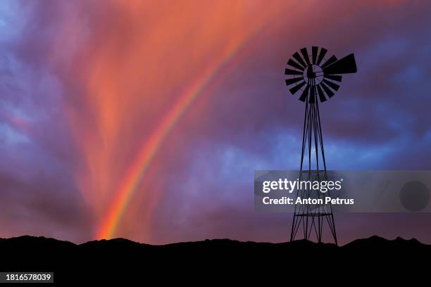 silhouette of a wind pump, windmill at sunset with rainbow - outback windmill bildbanksfoton och bilder