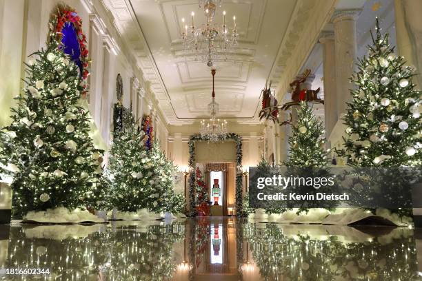 The Cross Hall between the East Room and the State Dining Room is lined with frosted Christmas tress during a media preview of the 2023 holiday...