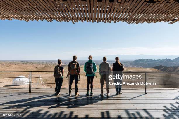 a group of five people with backpacks looking at a canyon in the desert and mountains. travel concept. - asia central fotografías e imágenes de stock