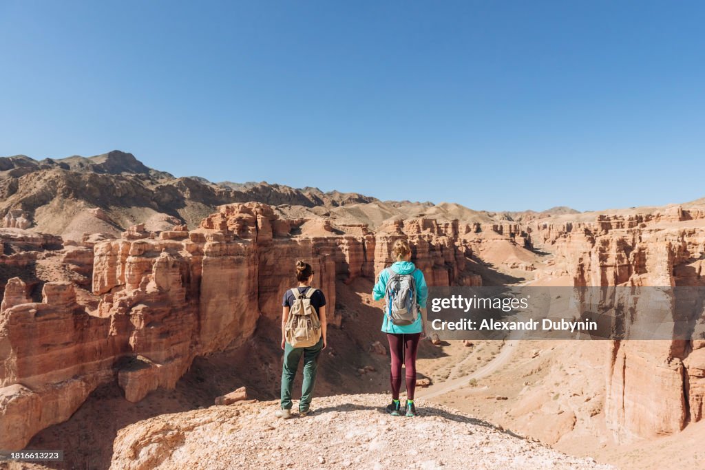 Two women with backpacks looking at the canyon. Travel concept.