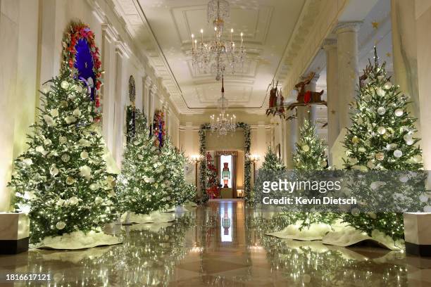 The Cross Hall between the East Room and the State Dining Room is lined with frosted Christmas tress during a media preview of the 2023 holiday...