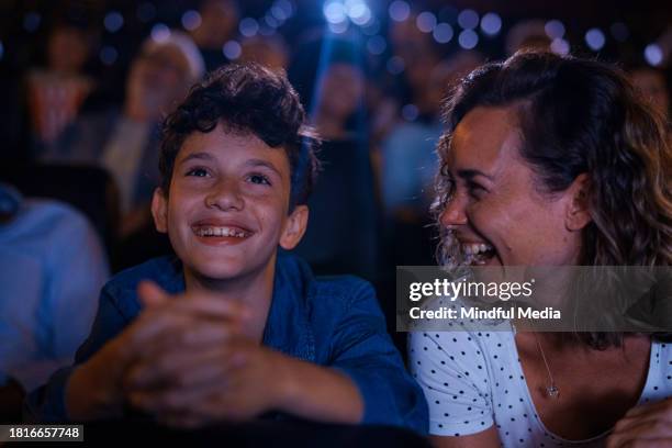mid-shot of cheerful young boy and his mother having fun at the movies - young couple watching movie at the movie theater stock pictures, royalty-free photos & images