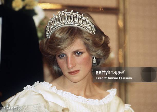 Diana, Princess of Wales, wearing a cream satin dress by Gina Fratini with the Queen Mary Cambridge Lover's Knot Tiara and diamond earrings attends a...