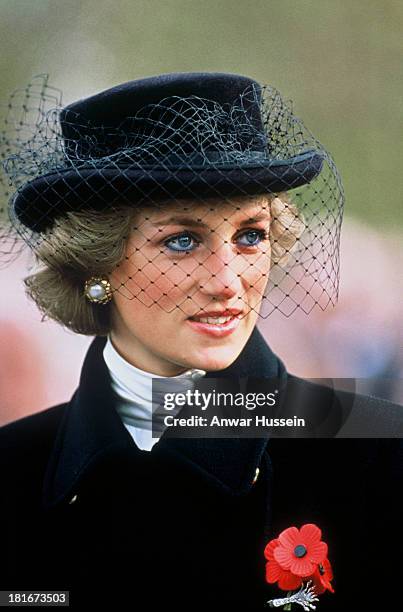 Diana, Princess of Wales, wearing a black coat with gold buttons designed by Jasper Conran, a black hat with netting designed by Viv Knowland and a...