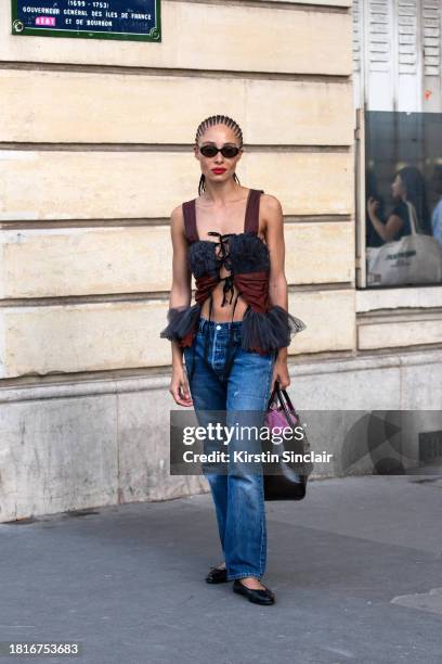 Adwoa Aboah wears a lace up top, blue jeans, black bag and sunglasses and black Chanel ballet shoes outside the Chloe show during the Womenswear...