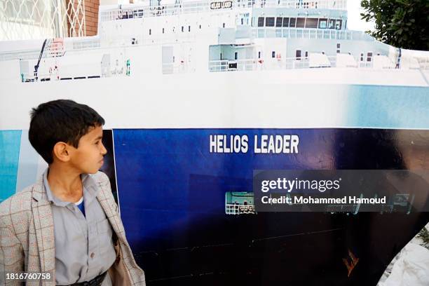 Yemeni child looks at a mock model of the Israeli Galaxy Leader cargo ship, seized by Houthi fighters displayed during an exhibition staged to...