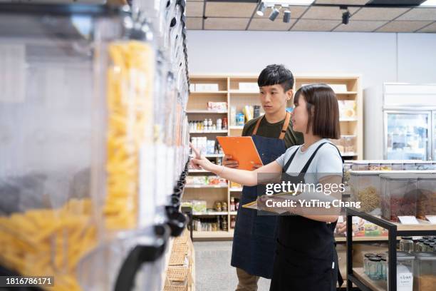 expertise in action: senior manager training new employee in health food store - loja de comida saudável imagens e fotografias de stock