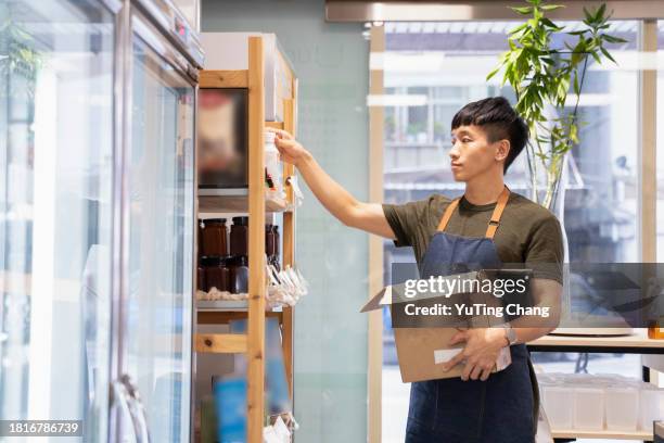 dedicated grocery shop employee restocking sustainable products - yuting stock pictures, royalty-free photos & images