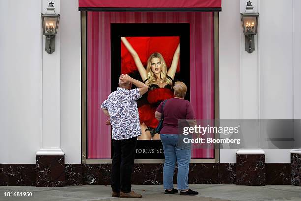 Shoppers stop to watch a video screen displayed outside of a Victoria's Secret Stores LLC location at Easton Town Center in Columbus, Ohio, U.S., on...