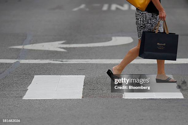 Pedestrian carries a Madewell & Madewell Inc. Shopping bag while crossing at Easton Town Center in Columbus, Ohio, U.S., on Friday, Sept. 20, 2013....