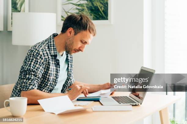 man using calculator and laptop computer to calculate numbers - steuererklärung stock-fotos und bilder
