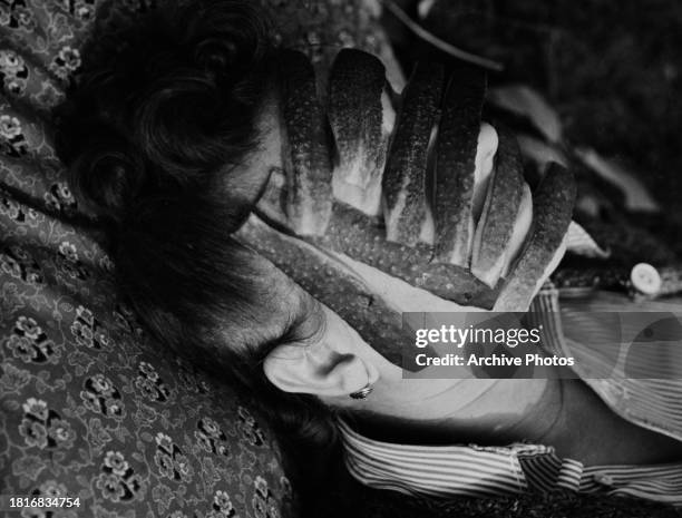 Reclining woman with sections of a squash draped across her face, in an attempt at rejuvenating her skin, United States, circa 1955.