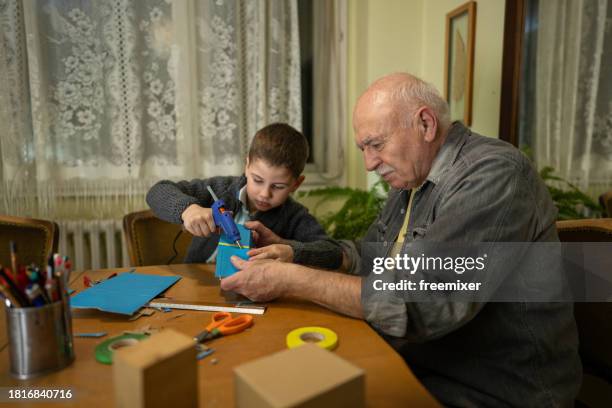 grandpa helping grandson with school project - glue gun stock pictures, royalty-free photos & images