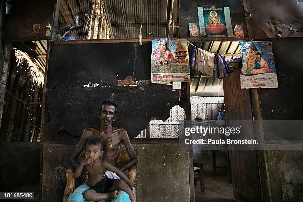 Rasan sits with his nephew Visnuvan in a camp for displaced Tamil families outside Jaffna, Sri Lanka, July 8, 2013. War's end has unleashed Sinhalese...