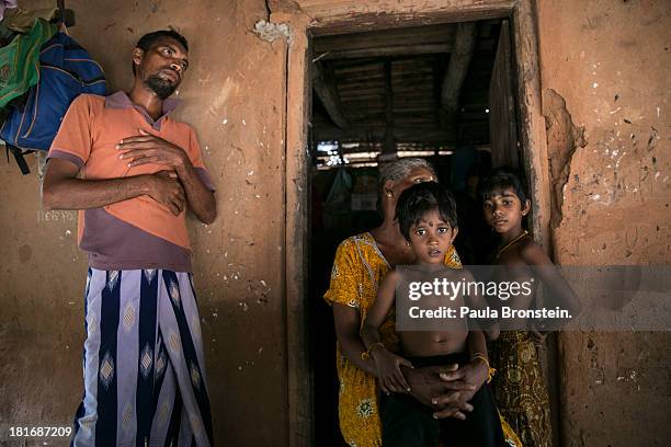 Gnanaseelan stands near his son Rajani with his grandmother, Indra Devi, and cousin Luxshagini outside their house in Mullaitivu, Sri Lanka, July 9,...