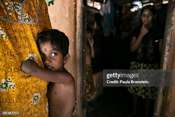 Tamil war victim Rajani grabs onto his grandmother, Indra Devi, outside their house in Mullaitivu, Sri Lanka, July 9, 2013. Rajani's mother was...