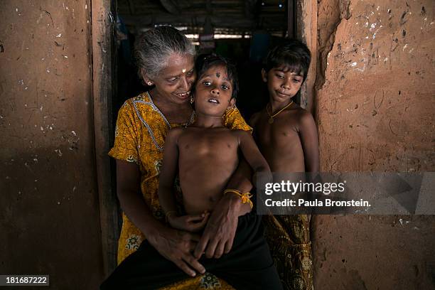 Tamil war victim Rajani sits on his grandmother's lap, Indra Devi, outside their house in Mullaitivu, Sri Lanka, July 9, 2013. Rajani's mother was...