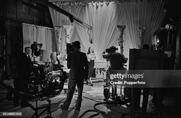 Production staff, floor staff and cameramen operating television cameras to film a performance by a female singer in a BBC television studio at...