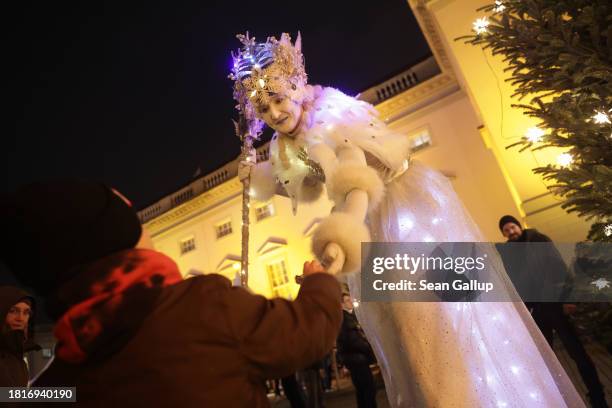 Theatrical performer on stilts offers a child a gift on the first day of the annual Gendarmenmarkt Christmas market on November 27, 2023 in Berlin,...