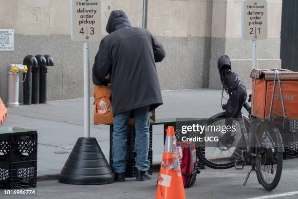 Worker at Instacart delivery order pickup area, outside Wegmans Astor Place.