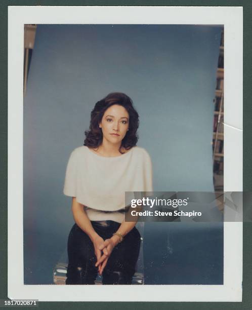 Portrait of English actress Olivia Hussey as she sits in front of a blue background, Los Angeles, California, 1984.