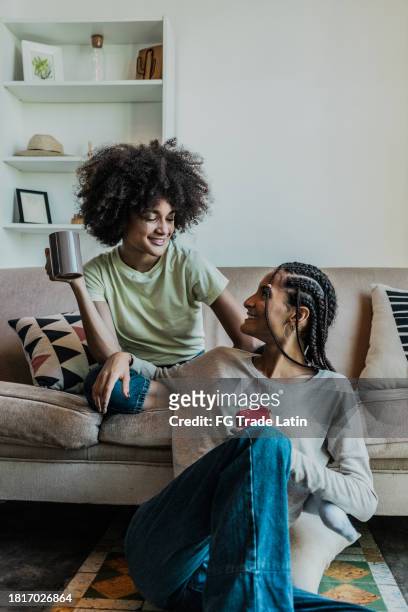 junge schwestern unterhalten sich zu hause im wohnzimmer - family on couch with mugs stock-fotos und bilder